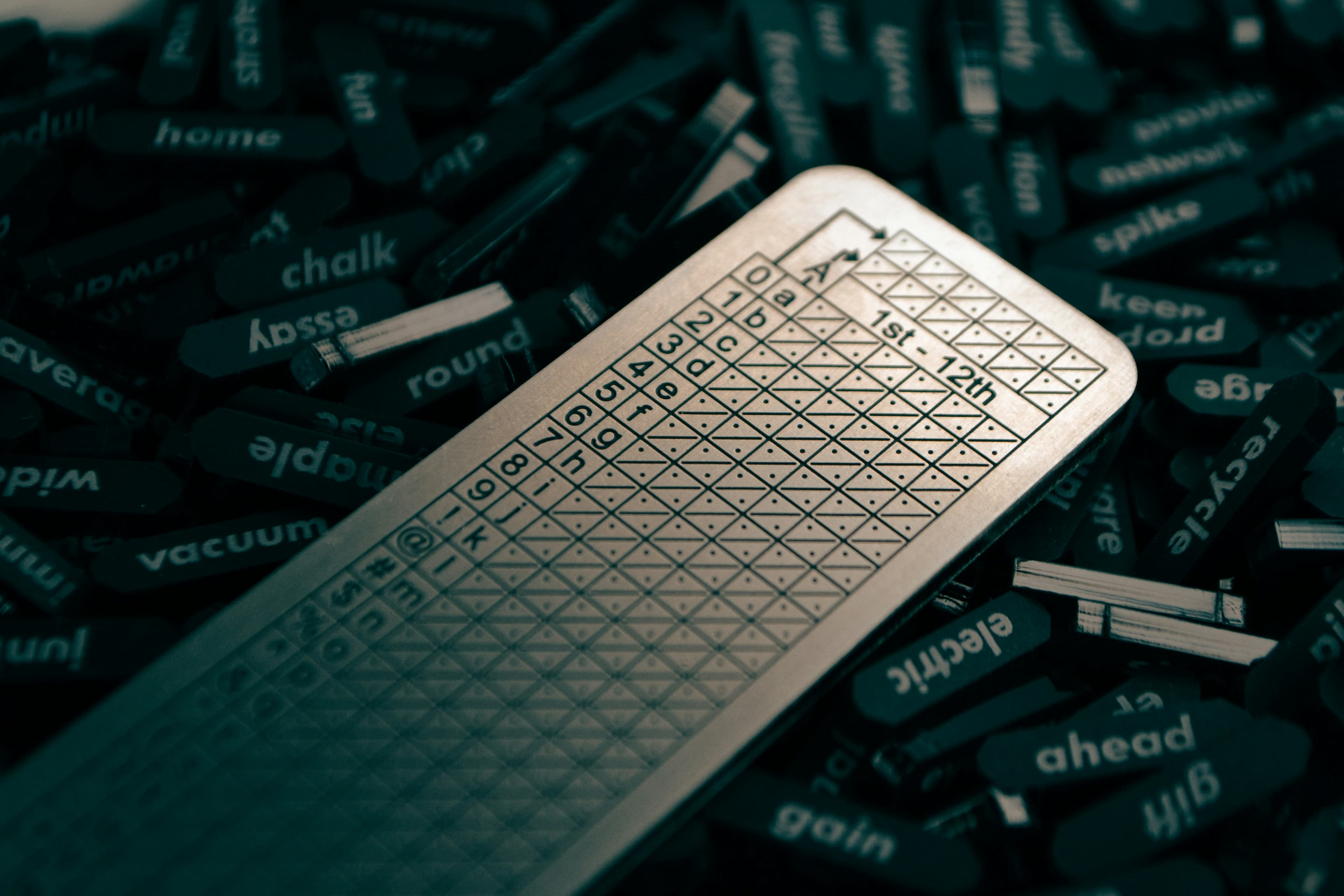 A steel backup plate for a recovery phrase on a pile of word tiles