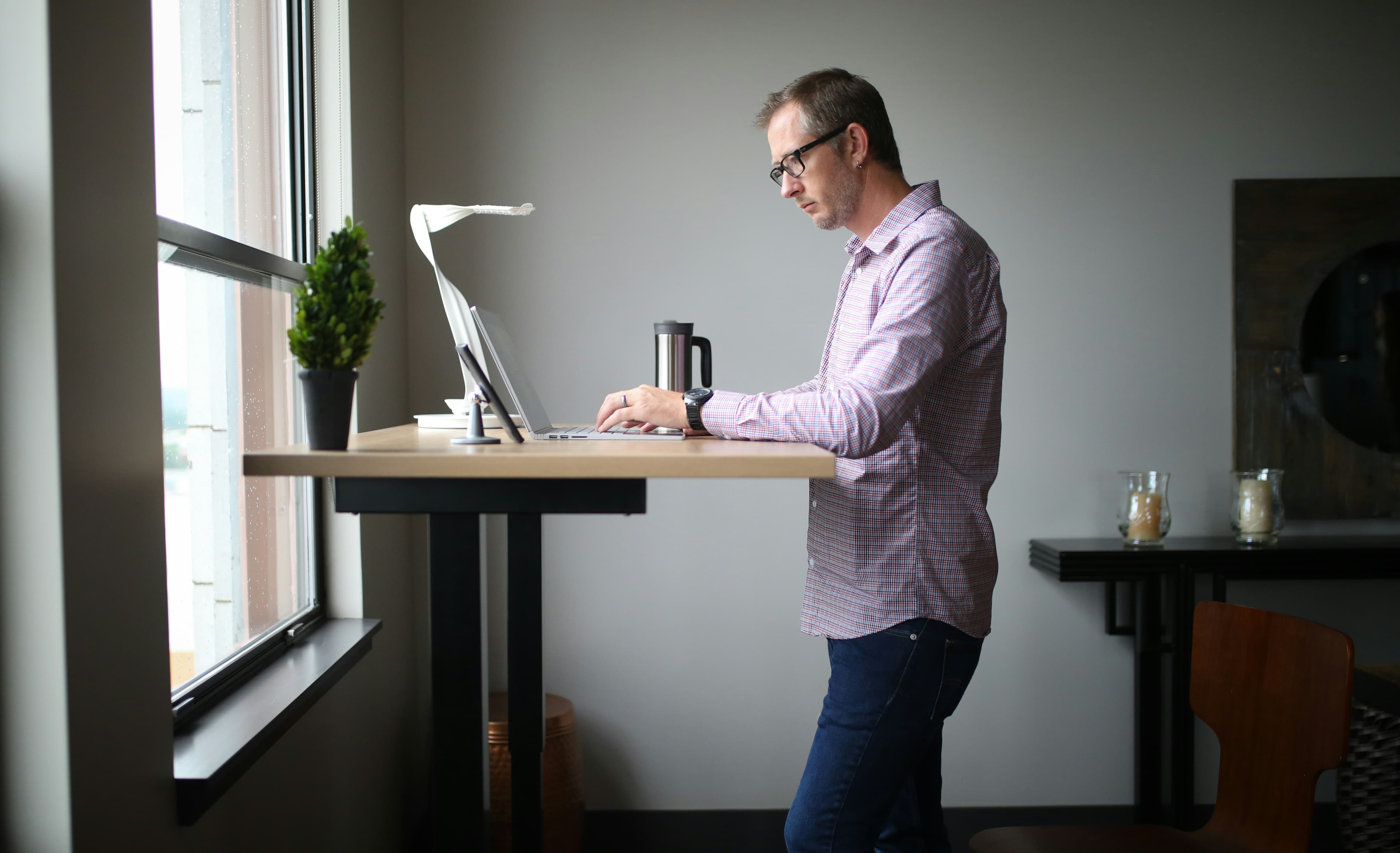 A man working at a standing desk by a window